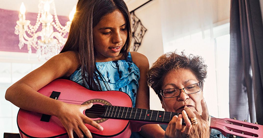 Girl playing the charango to her grandma